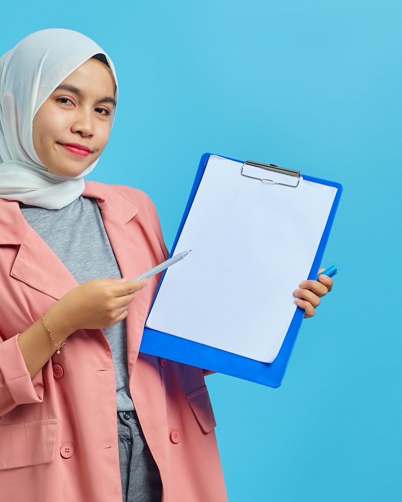 Perempuan berhijab memegang papan klip
