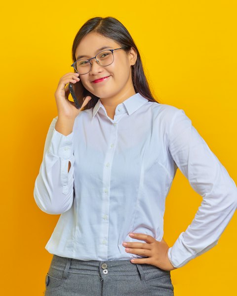 Perempuan berkacamata menelepon sambil tersenyum